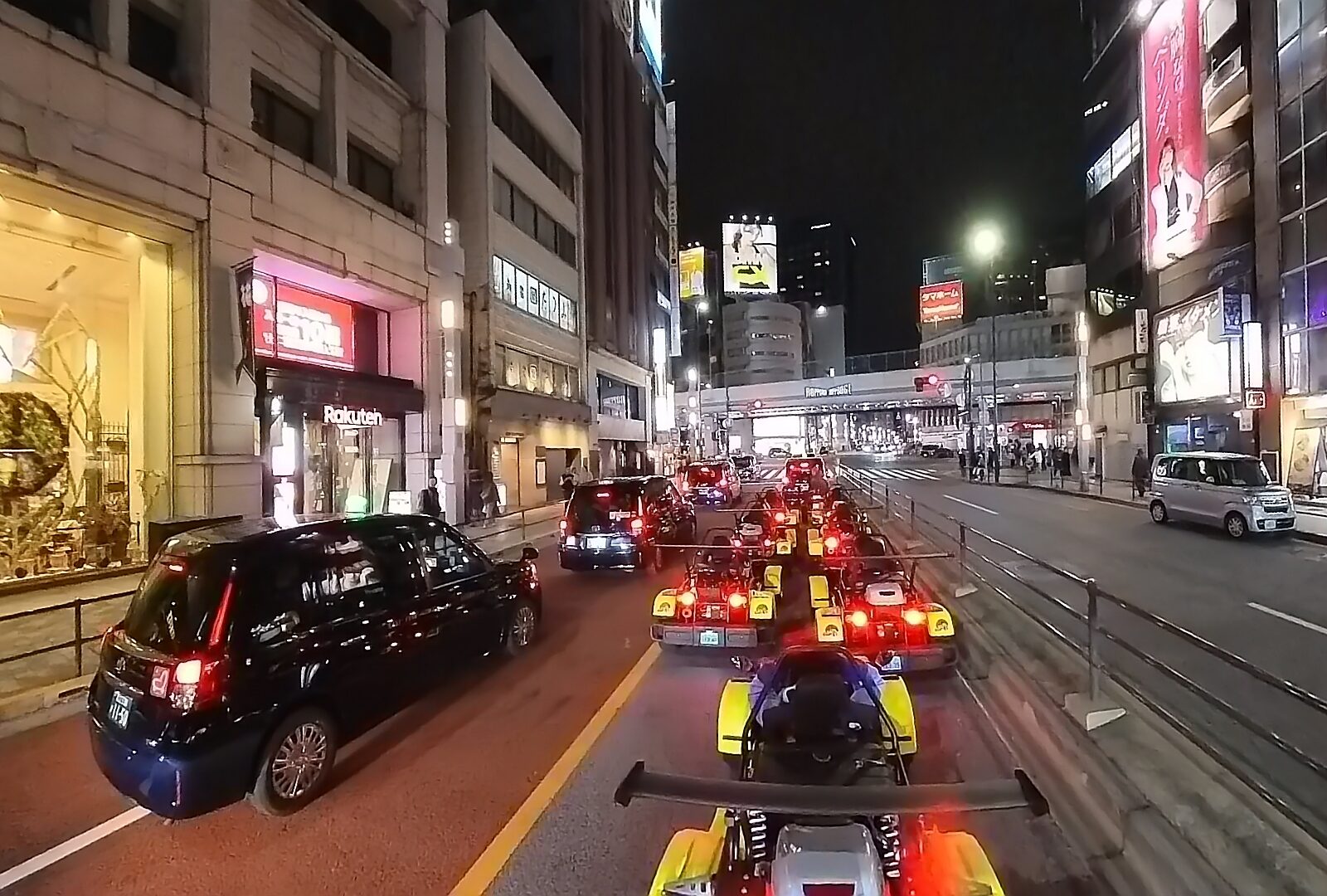 Bright yellow Kartzilla Go Karts cruising down Roppongi Dori, surrounded by neon-lit streets, buildings, in the vibrant nightlife of Tokyo.
