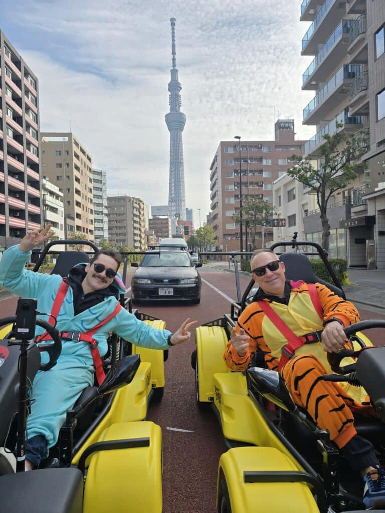 Go-kart riders in costume pose in front of Tokyo Skytree during a Kartzilla Go Kart tour.