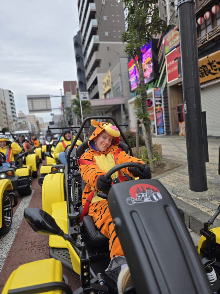 Smiling go-kart rider in a Tigger costume leads a group tour through Sumida’s colorful streets with Kartzilla Go Kart in Tokyo.