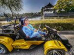 Tourist in blue costume smiling while driving a Mario Kart style go-kart Tokyo street kart near the Imperial Palace during a Kartzilla Go Kart tour.
