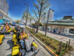 Group of tourists in costume driving Mario Kart style go-karts past Ryōgoku Sumo Stadium during a go-kart Tokyo street kart tour with Kartzilla.
