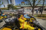 Tourists in Pikachu and Stitch costumes driving Mario Kart style go-karts past Ryōgoku Sumo Stadium during a go-kart Tokyo street kart tour with Kartzilla.