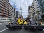 Tourists driving Mario Kart style go-karts in Tokyo with Tokyo Skytree in the background during a street kart tour by Kartzilla Go Kart.