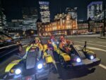 Tourists wearing anime costumes posing in front of Tokyo Station at night during a go-kart Tokyo tour with Kartzilla.