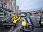 Two tourists in Pikachu and Stitch costumes driving Mario Kart style go-karts through Ueno, Tokyo during a street kart tour with Kartzilla Go Kart.
