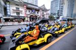 Group of tourists in colorful costumes driving Mario Kart style go-karts past Kabukiza Theater in Tokyo during a Kartzilla Go Kart street kart tour.
