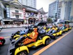 Group of tourists in colorful costumes driving Mario Kart style go-karts past Kabukiza Theater in Tokyo during a Kartzilla Go Kart street kart tour.