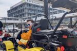 Tourist wearing costume and sunglasses driving a Mario Kart style street kart near Toyosu Market on a Kartzilla Go Kart Tokyo tour.